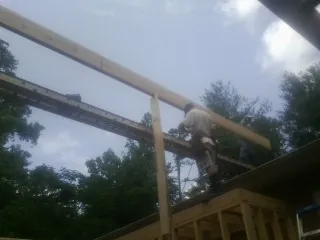 Carpenter setting a ridge beam over a new addition frame — Ice Dam Removal by Roofing Brothers in Wilson