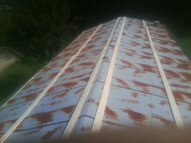 Rusted metal roof panels with new wood purlins before replacement in Wilson